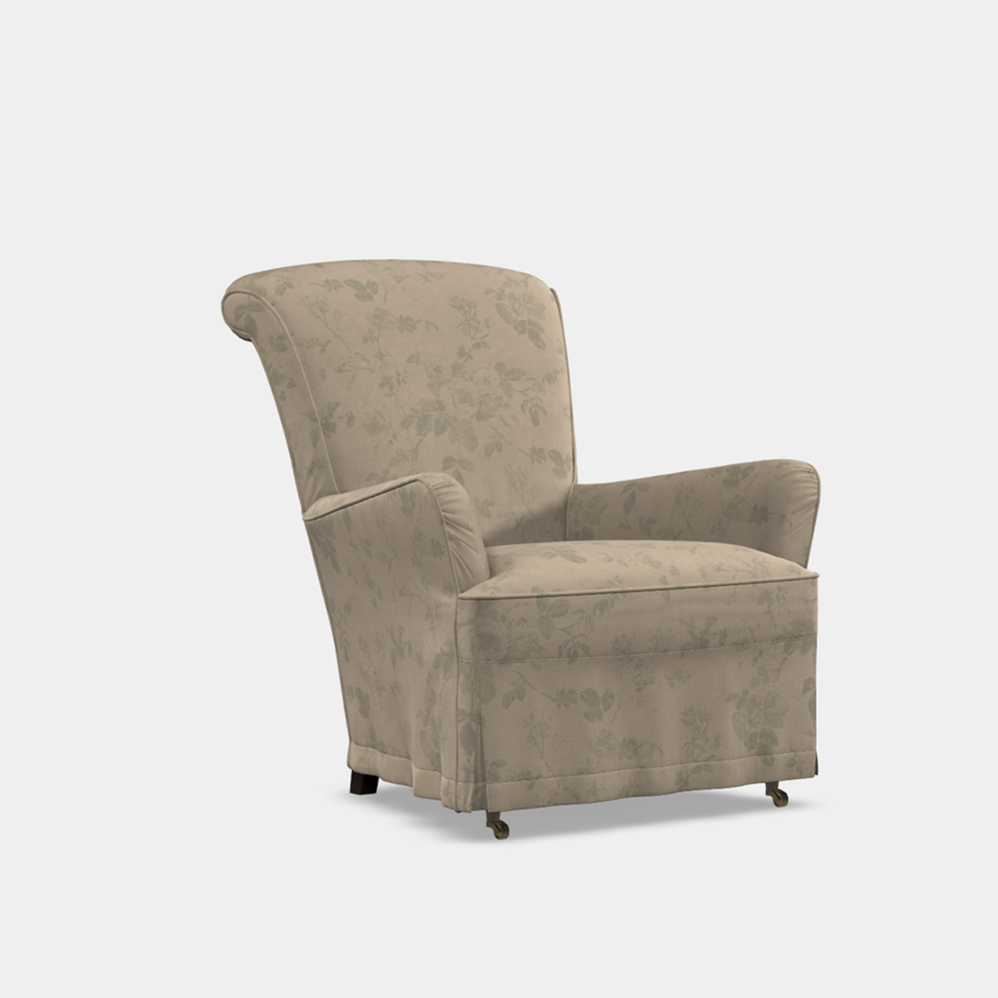 A beige upholstered slipcover chair with an inclined scrolled back, suitable for a quiet corner in a home.