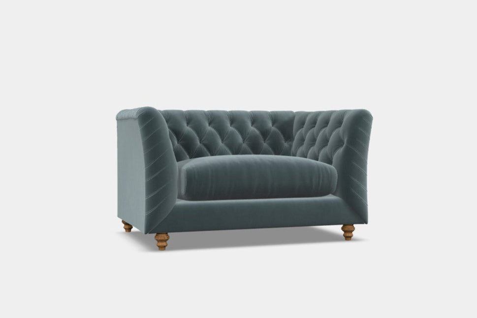 A contemporary blue chesterfield sofa with deep button detail and hardwood feet, designed for elegant lounging in living spaces.