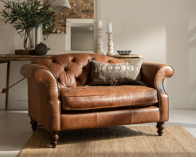 Brown leather sofa in a living room with a mirror and decorative items.