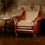 Vintage-style armchair with leather and fabric details against a textured wall.