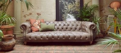 Decorative living room with a gray sofa, plants, and a framed picture on a brick wall.