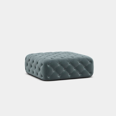 A gray upholstered footstool with deep button detailing, presented against a white background.