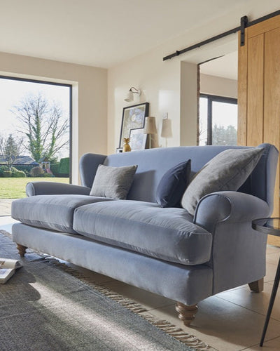 Living room with a gray sofa, armchair, and large windows.